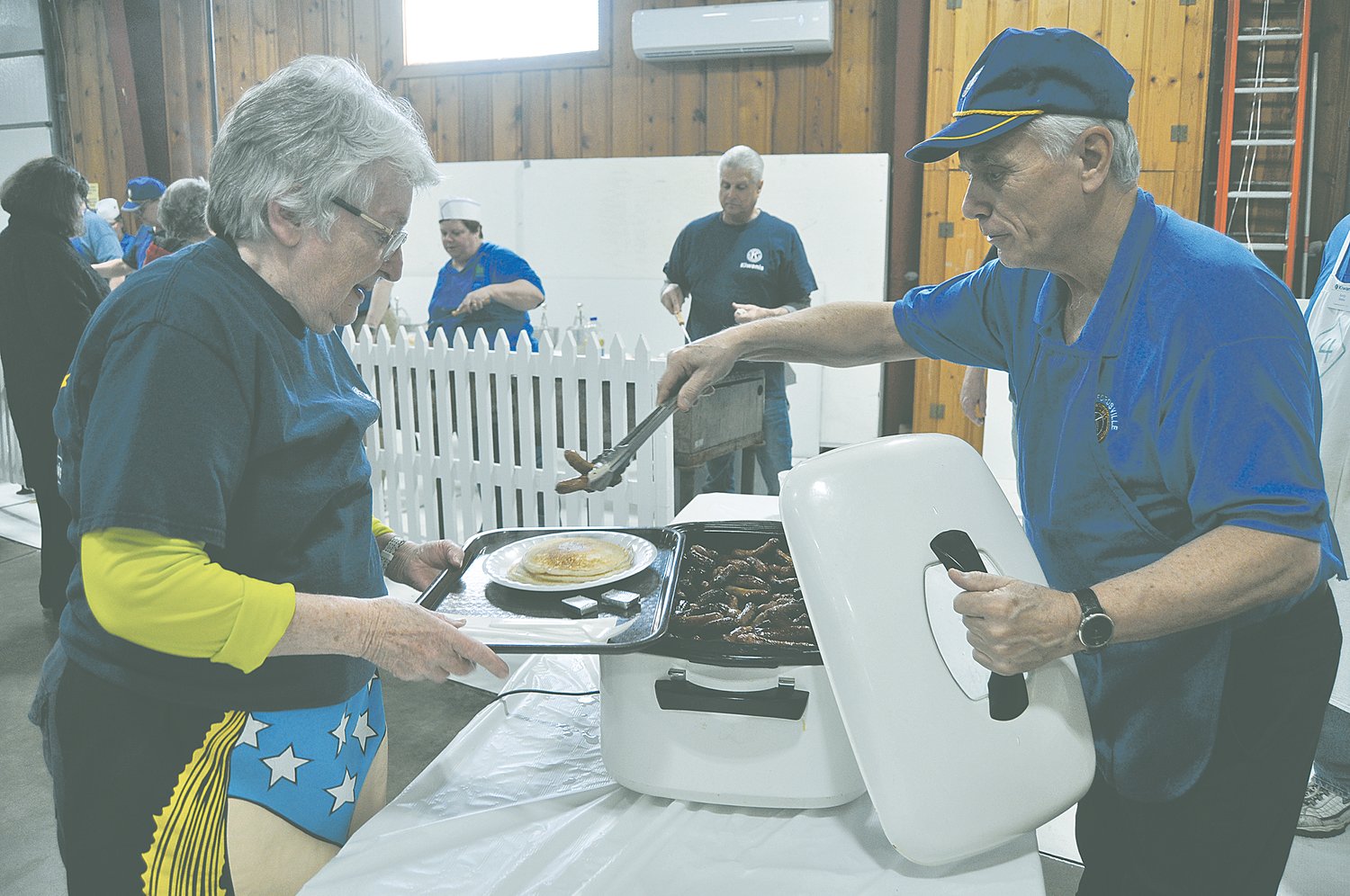 S. David Long serves sausages to Diane Kreisher at a Crawfordsville Kiwanis Pancake Day. Long is recovering from a battle with COVID-19.